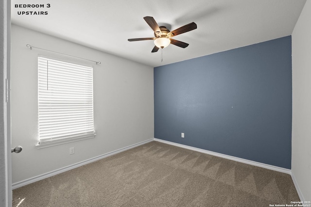spare room featuring ceiling fan, carpet flooring, and baseboards
