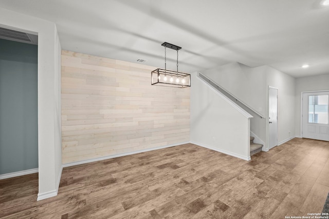 unfurnished dining area featuring wood finished floors, baseboards, stairs, recessed lighting, and wooden walls