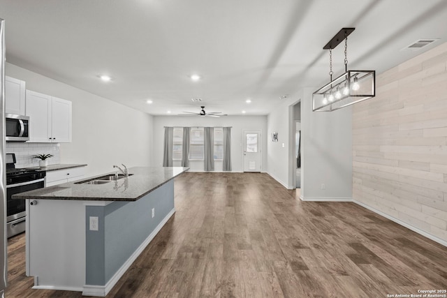 kitchen with stainless steel appliances, a sink, white cabinets, recessed lighting, and dark wood-style floors