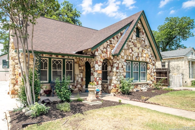 243 N, San Antonio, TX 78201 - tudor-style house with stone siding, roof with shingles, and covered porch