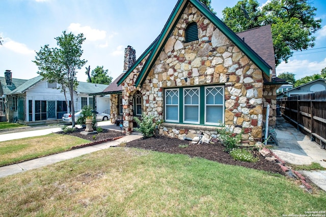 243 N, San Antonio, TX 78201 - tudor house featuring stone siding, a chimney, a shingled roof, and a patio area