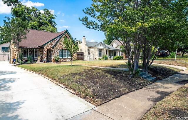 243 N, San Antonio, TX 78201 - view of front of house with stone siding, a front lawn, and roof with shingles