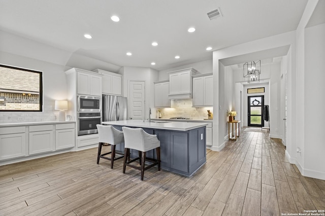 435 Bridle Trl, New Braunfels, TX 78132 - kitchen with appliances with stainless steel finishes, light wood-style flooring, light countertops, decorative backsplash, and white cabinets