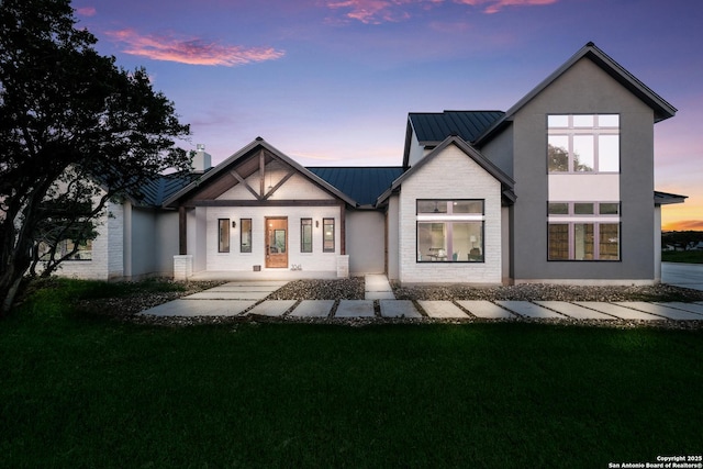 3045 Campestres, Spring Branch, TX 78070 - back of property at dusk featuring a standing seam roof, a yard, metal roof, and stucco siding