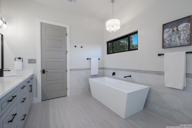 3045 Campestres, Spring Branch, TX 78070 - full bathroom with tile walls, a chandelier, a freestanding bath, vanity, and wainscoting