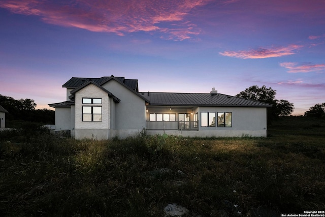 3045 Campestres, Spring Branch, TX 78070 - back of house at dusk featuring a standing seam roof, metal roof, a chimney, and stucco siding