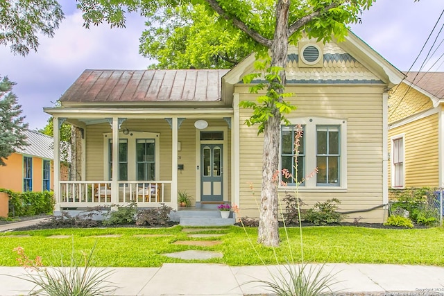 view of front facade with a front lawn, covered porch, a standing seam roof, and metal roof
