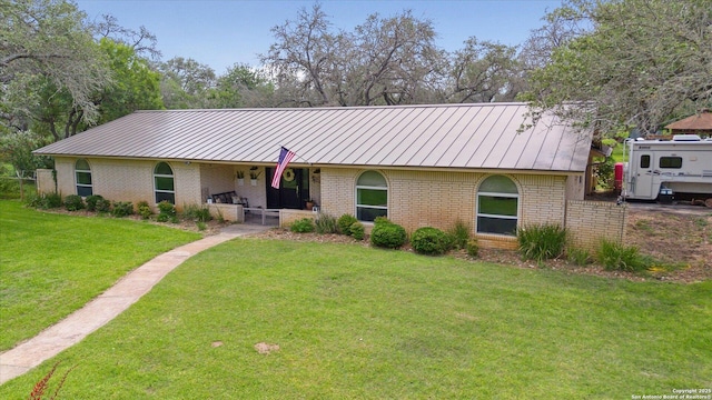 101 Cynthia, Pleasanton, TX 78064 - view of front facade featuring a porch, a standing seam roof, brick siding, a front lawn, and metal roof