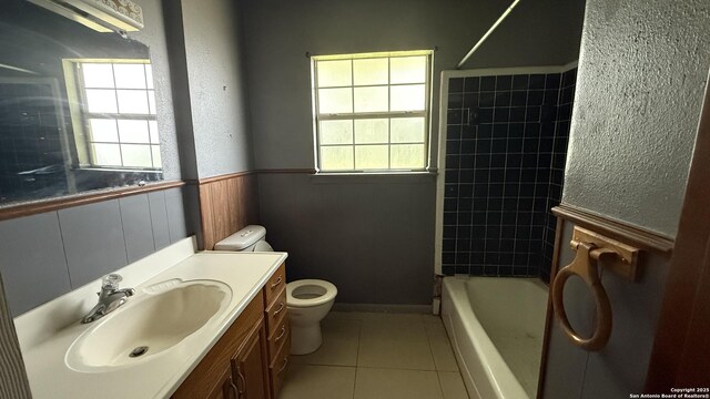 1906 Perlita, San Antonio, TX 78224 - bathroom with toilet, tile patterned flooring, vanity, a wainscoted wall, and tub / shower combination