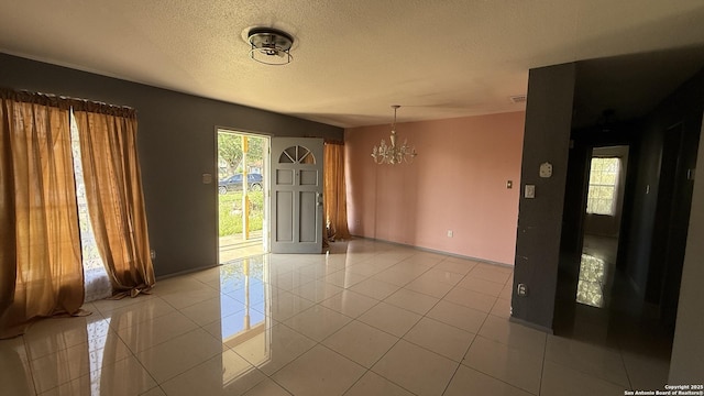 1906 Perlita, San Antonio, TX 78224 - unfurnished room featuring a chandelier, light tile patterned flooring, baseboards, and a textured ceiling