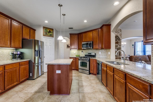 kitchen with stainless steel appliances, a sink, arched walkways, decorative backsplash, and a center island