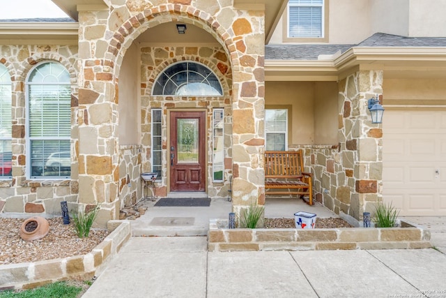 view of exterior entry with stucco siding, stone siding, and a garage