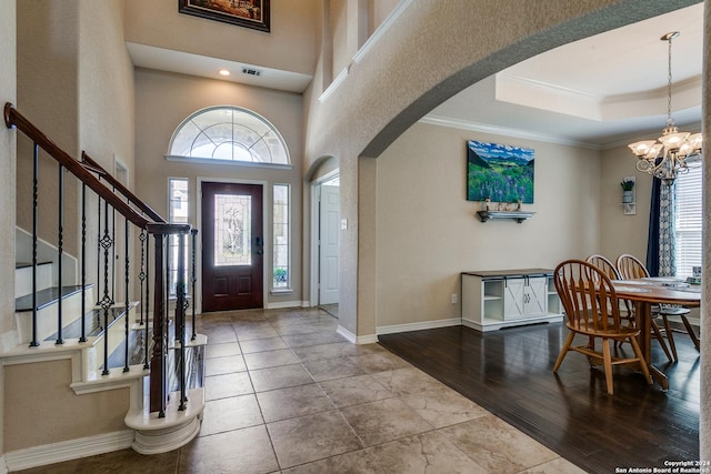entrance foyer with a chandelier, arched walkways, stairway, crown molding, and baseboards