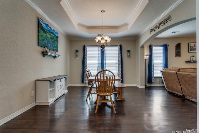 dining area with plenty of natural light, a chandelier, a raised ceiling, crown molding, and dark wood-type flooring