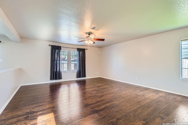 spare room featuring dark wood-style floors, a ceiling fan, a textured ceiling, and baseboards