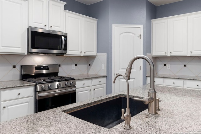 10607 Carmona, Helotes, TX 78023 - kitchen featuring appliances with stainless steel finishes, white cabinets, tasteful backsplash, light stone counters, and a sink