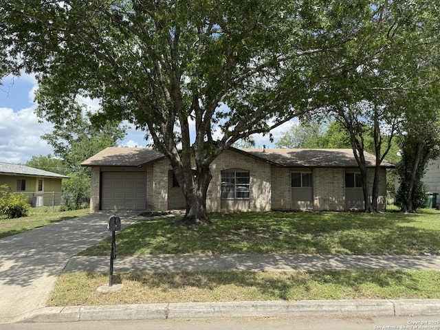 ranch-style home featuring brick siding, an attached garage, concrete driveway, and a front lawn