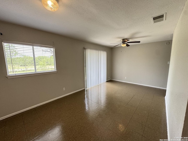 empty room with a ceiling fan, baseboards, and a textured ceiling