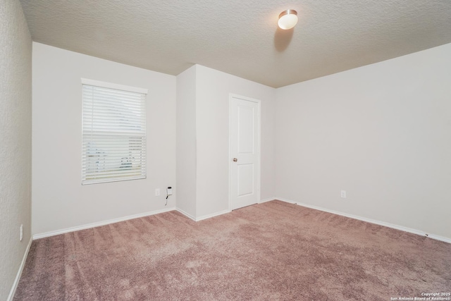 unfurnished room with carpet floors, baseboards, and a textured ceiling