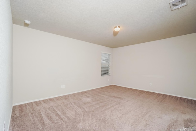 spare room with carpet floors, baseboards, a smoke detector, and a textured ceiling