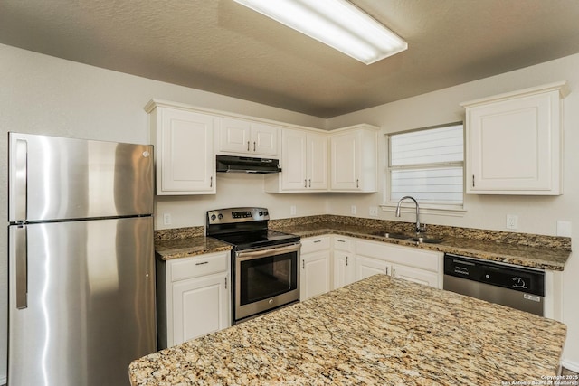 5503 Hidden, San Antonio, TX 78252 - kitchen with appliances with stainless steel finishes, a sink, under cabinet range hood, dark stone counters, and white cabinetry