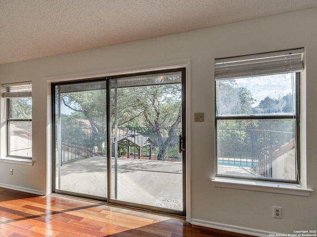 12802 Country Crst, San Antonio, TX 78216 - doorway featuring wood finished floors, baseboards, healthy amount of natural light, and a textured ceiling