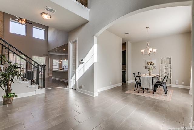 entryway featuring arched walkways, stairs, a towering ceiling, baseboards, and a chandelier