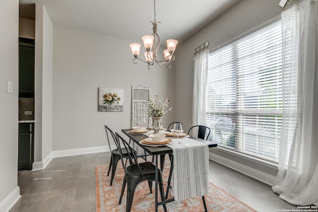 dining space featuring a chandelier and baseboards