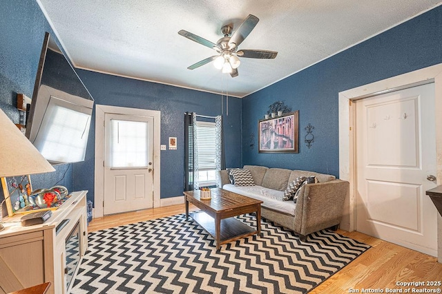 1004 Leona, Cotulla, TX 78014 - living room with light wood-style flooring, ceiling fan, a textured ceiling, and a textured wall