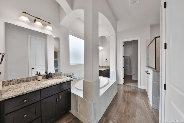 6514 Comanche Post, San Antonio, TX 78233 - bathroom featuring a shower stall, a garden tub, two vanities, a spacious closet, and wood finished floors