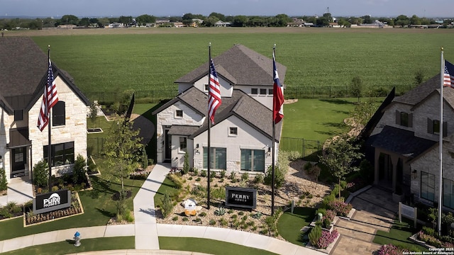 view of front of house featuring a rural view, stone siding, and fence