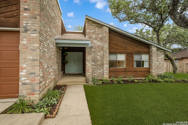 view of front of property featuring a front yard, brick siding, and an attached garage