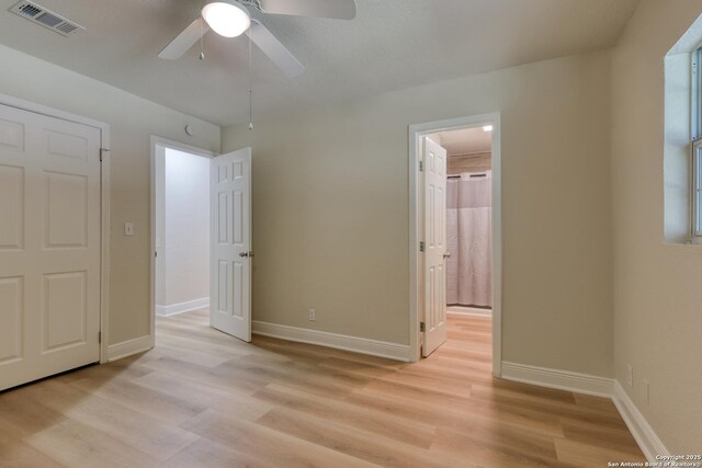 9015 Spanish Cv, San Antonio, TX 78242 - unfurnished bedroom featuring light wood-style flooring, baseboards, ensuite bath, and a ceiling fan