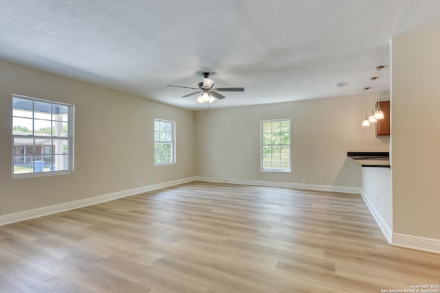 9015 Spanish Cv, San Antonio, TX 78242 - empty room with light wood-style flooring, a textured ceiling, ceiling fan, baseboards, and a chandelier