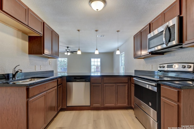 9015 Spanish Cv, San Antonio, TX 78242 - kitchen with appliances with stainless steel finishes, a sink, a peninsula, light wood-type flooring, and ceiling fan