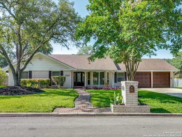 ranch-style home with a garage, brick siding, a front lawn, and driveway