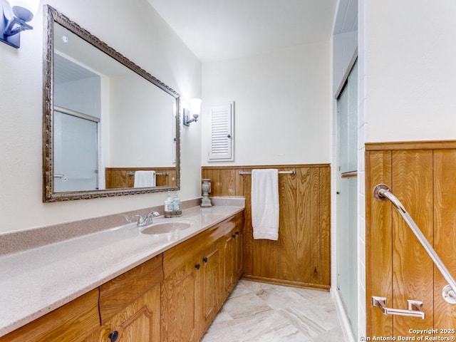 bathroom featuring vanity, an enclosed shower, and wainscoting