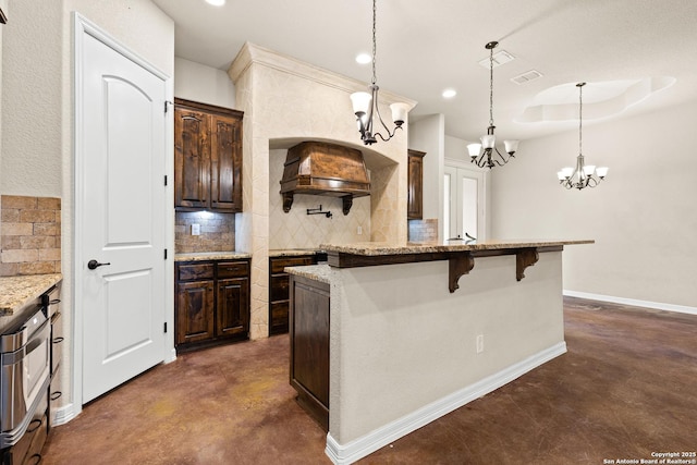 105 Saddle Up, La Vernia, TX 78121 - kitchen with finished concrete flooring, a chandelier, decorative backsplash, dark brown cabinets, and recessed lighting