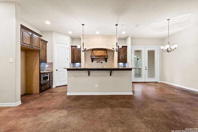 105 Saddle Up, La Vernia, TX 78121 - kitchen featuring tasteful backsplash, an island with sink, baseboards, a chandelier, and recessed lighting