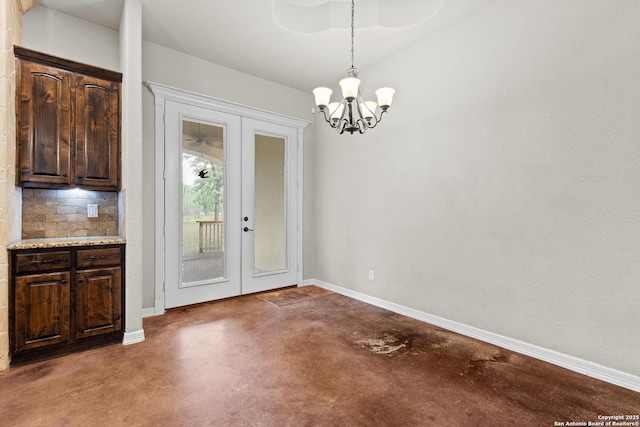 105 Saddle Up, La Vernia, TX 78121 - unfurnished dining area with concrete flooring, french doors, a chandelier, and baseboards