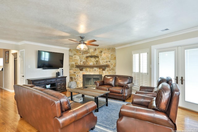 living area with crown molding, ceiling fan, light wood-style flooring, a fireplace, and baseboards