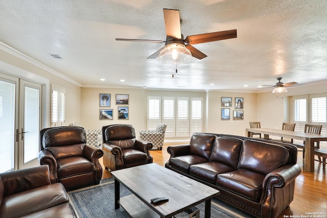 living area with ceiling fan, light wood-type flooring, crown molding, recessed lighting, and a textured ceiling