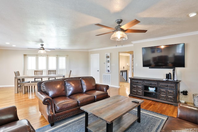 living area with a ceiling fan, wood finished floors, crown molding, baseboards, and a textured ceiling