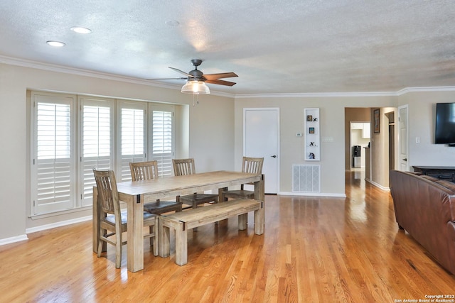 dining area with a ceiling fan, light wood-style floors, a textured ceiling, ornamental molding, and baseboards