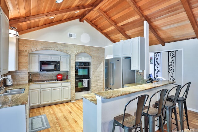 kitchen featuring black appliances, a sink, wooden ceiling, light wood-style floors, and a peninsula