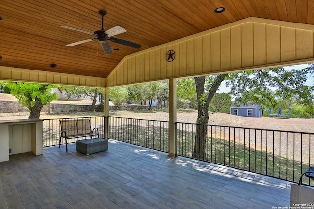 wooden deck featuring a ceiling fan, a shed, and an outdoor structure