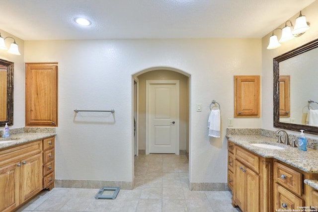 full bathroom with baseboards, two vanities, and tile patterned flooring