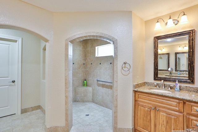 bathroom with tiled shower, vanity, and tile patterned flooring