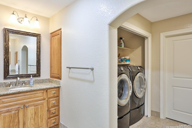 laundry room featuring washer and dryer, arched walkways, and light tile patterned flooring