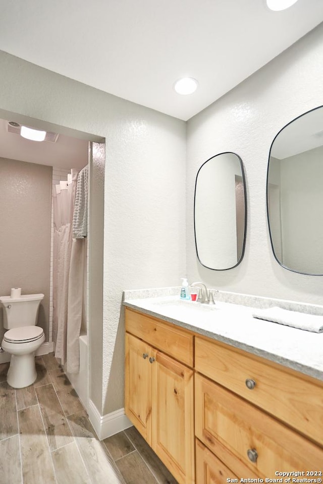 full bath featuring toilet, vanity, wood tiled floors, a textured wall, and shower / tub combo with curtain